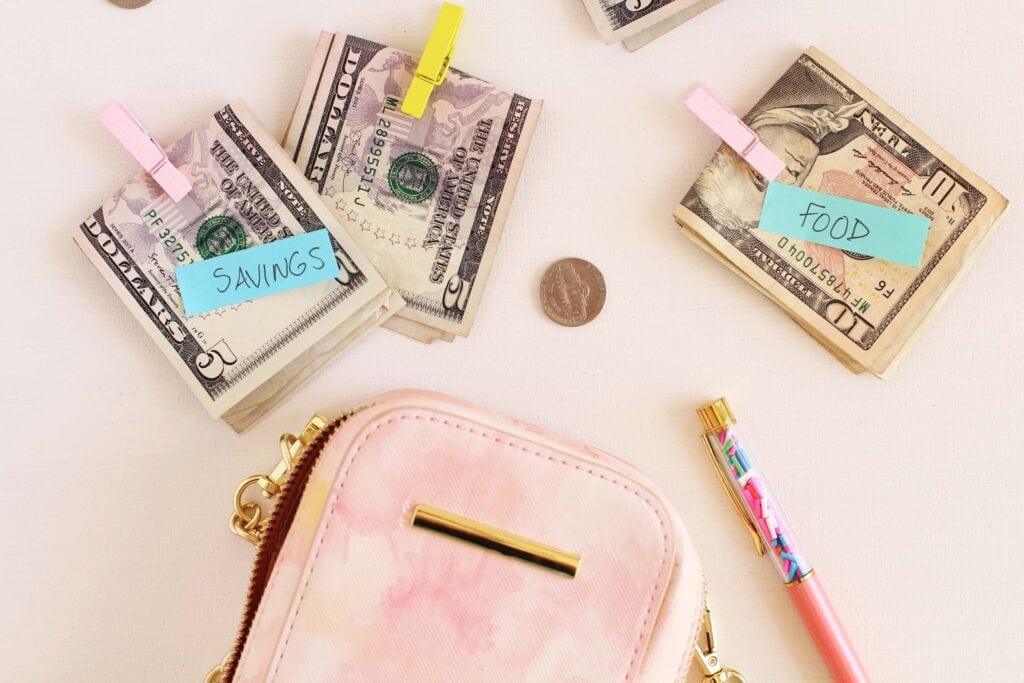 picture of money on table with labels "savings" and "food" for article how to save $10 000 in a year